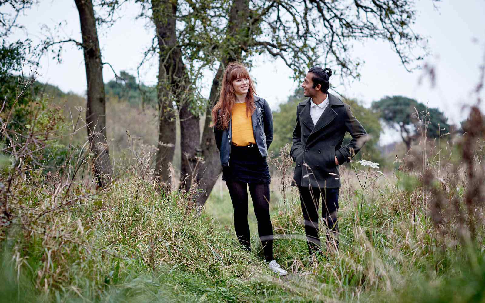 Two students walk in a woodland area. 
