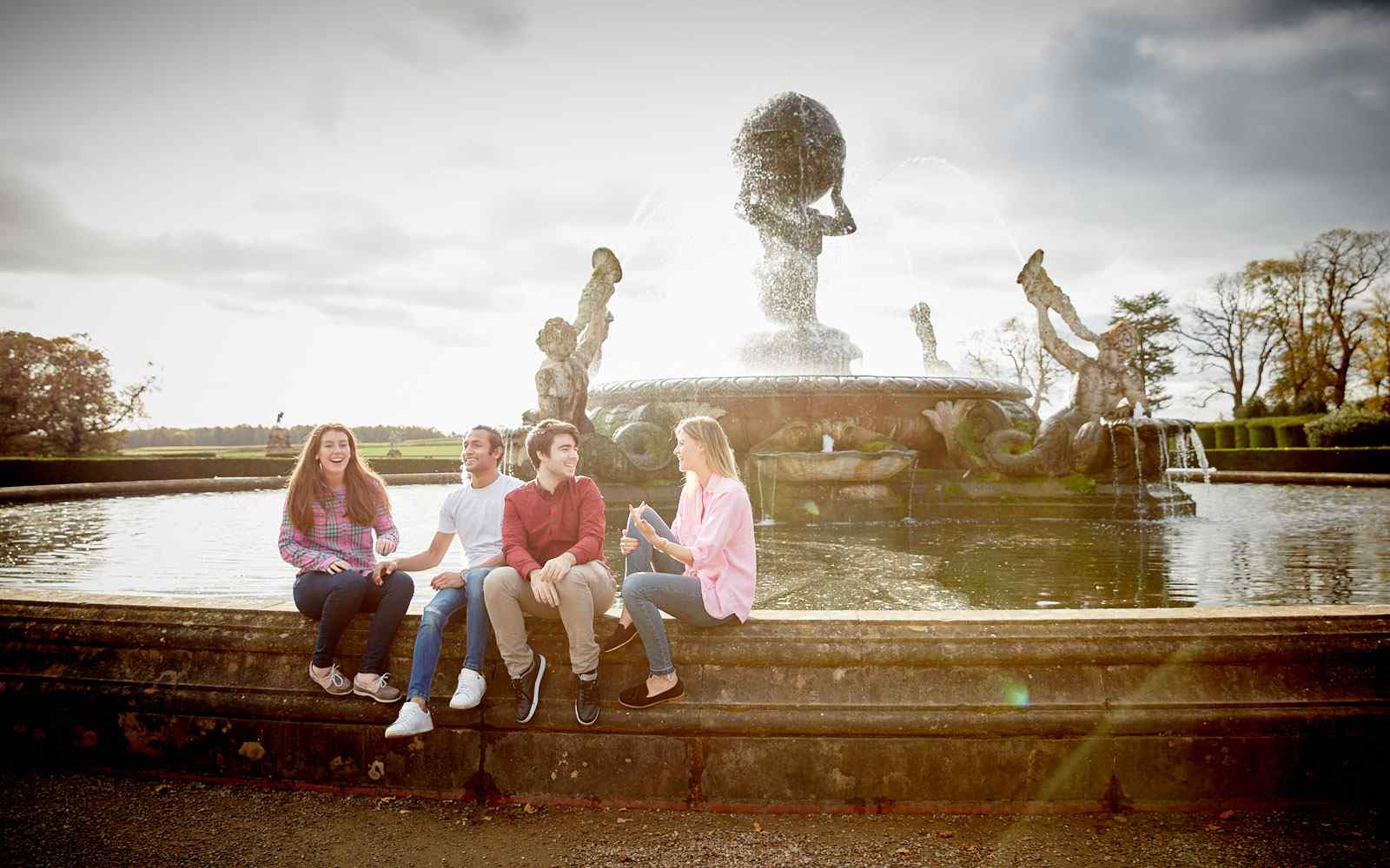 Students sitting on fountain at castle howard 