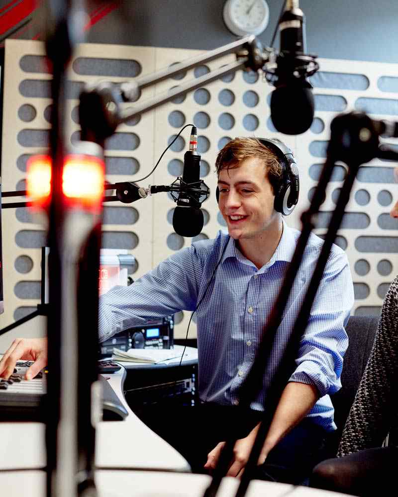 Journalism student in radio recording studio, speaking into microphone 