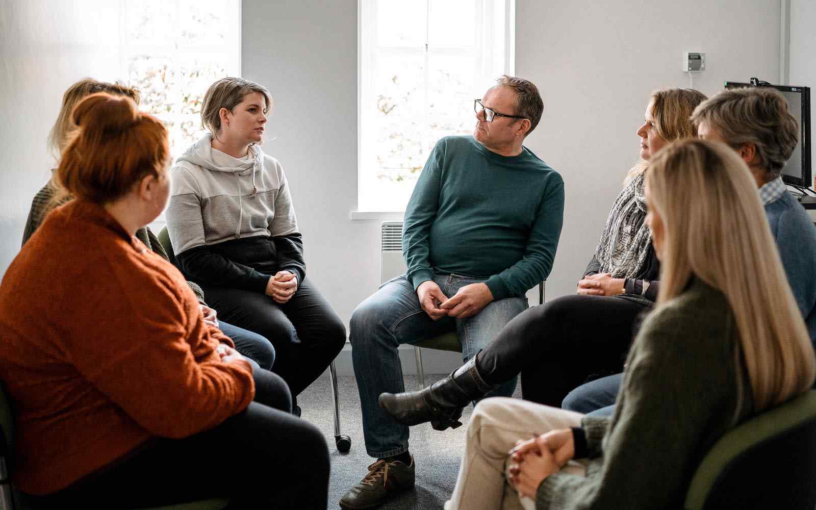 Group of counselling students sat in circle in discussion 