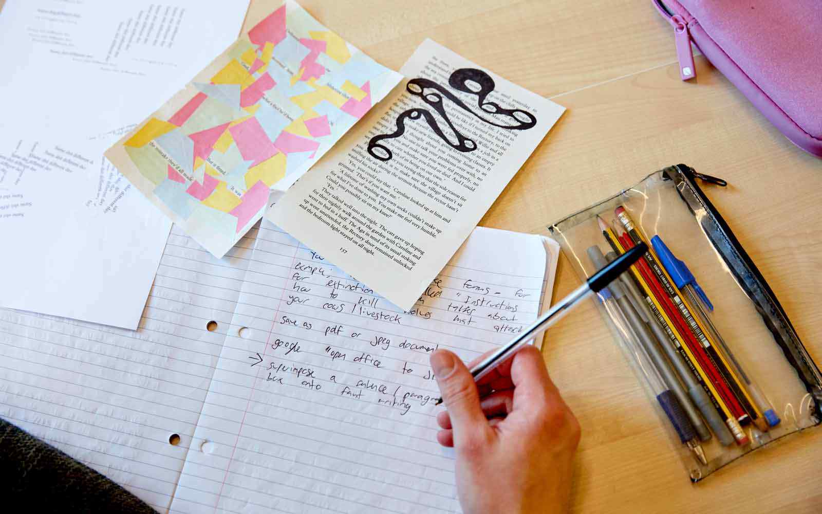 Overhead view of a student writing work at a desk. 