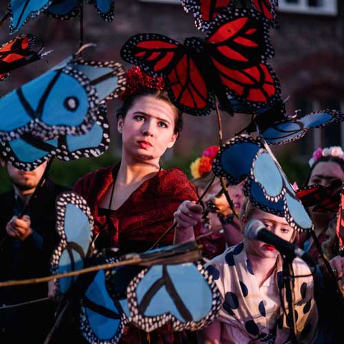 Performers holding butterfly puppets outside 