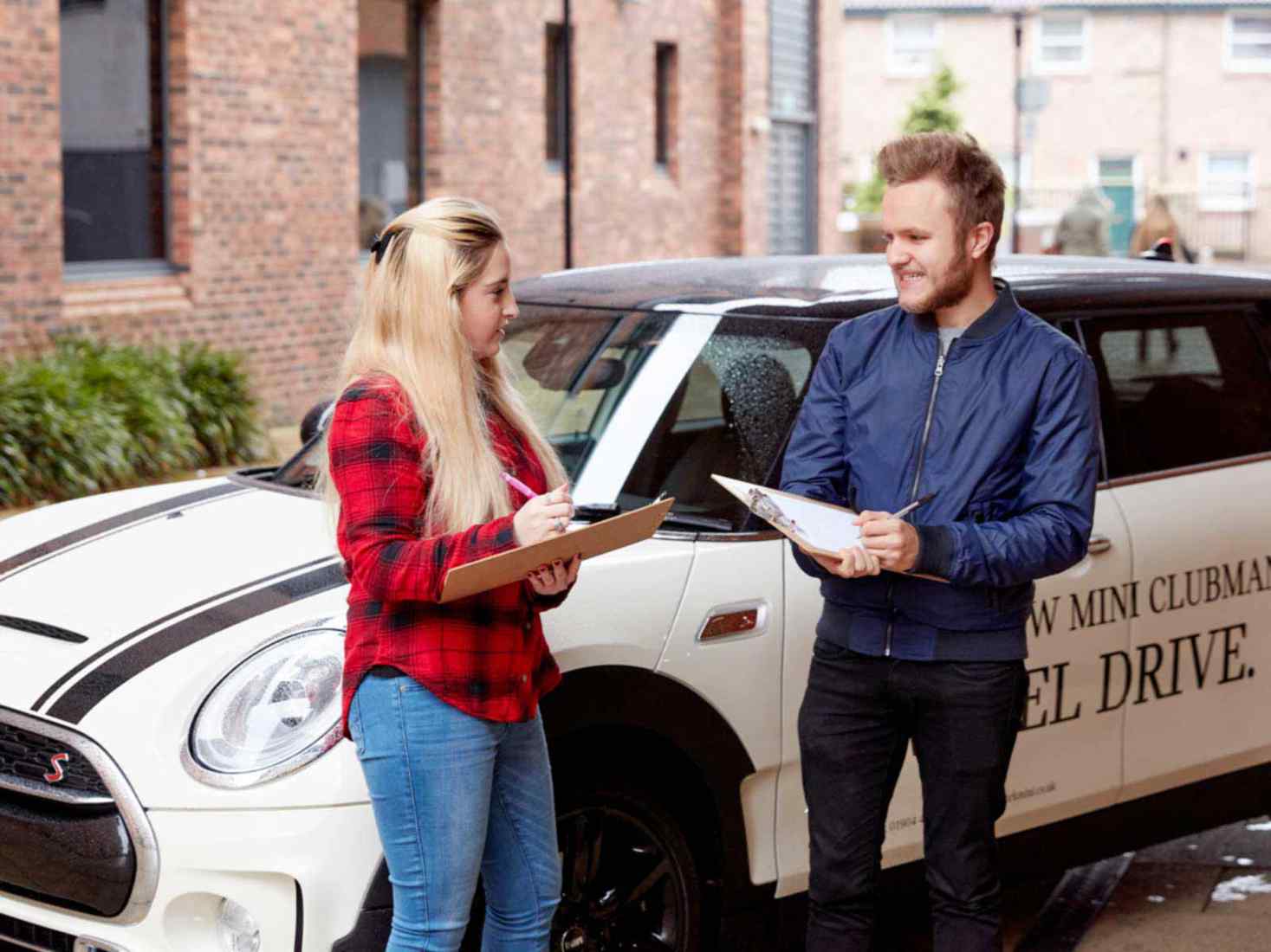 Two young people talking in front of a car 