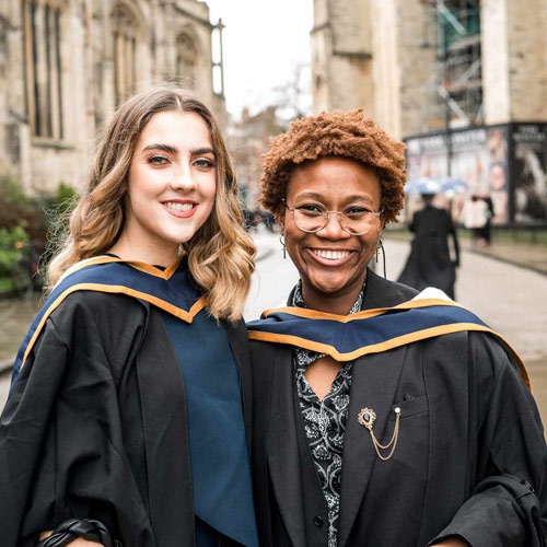 Two students in graduation gowns outside York Minster. 