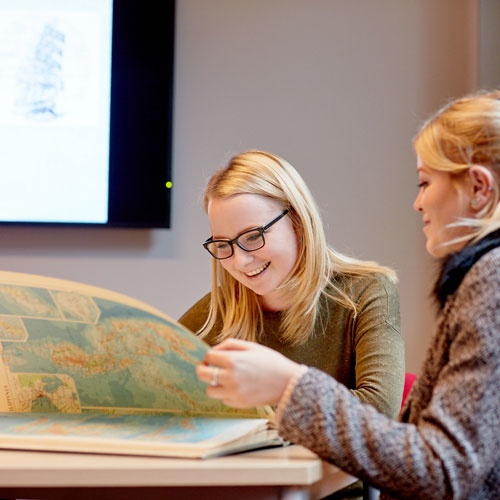 History students looking at map book 