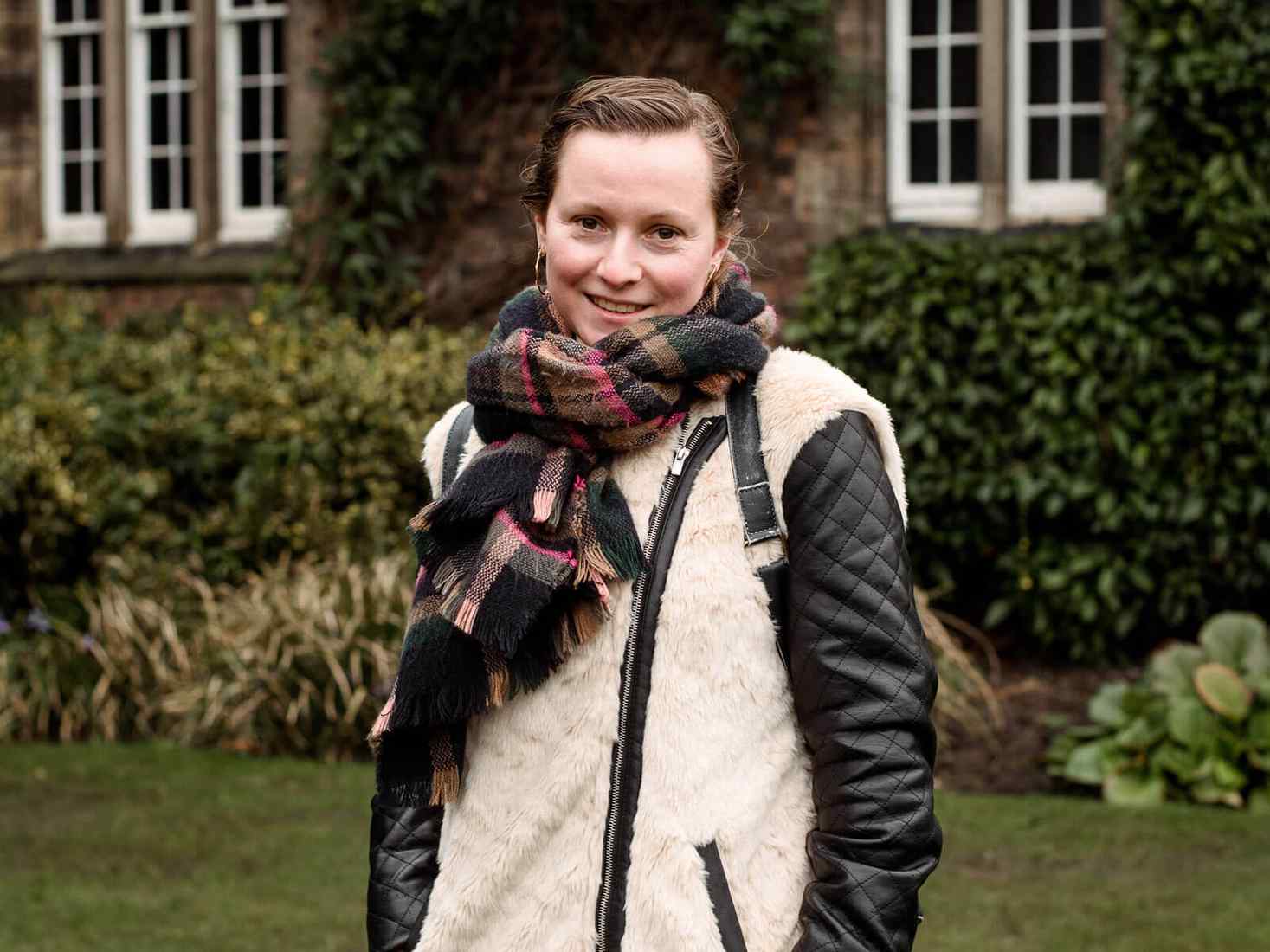 Student wearing a scarf stood in front of campus building 
