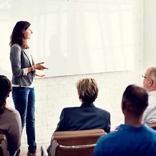 Business person presenting to audience in front of whiteboard 