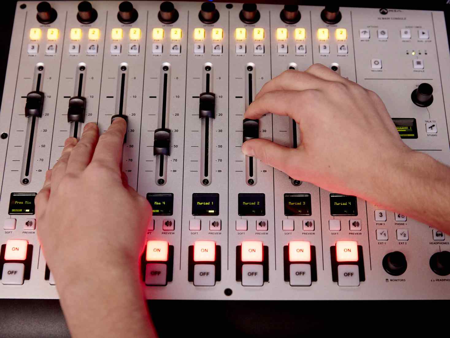 Hands moving levels on recording desk 
