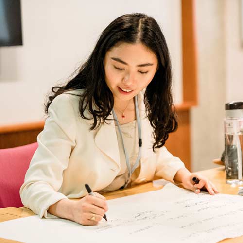 Law student wearing business wear and writing notes on large piece of paper 
