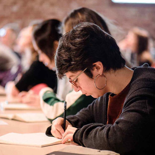 A student writes notes during a lecture. 