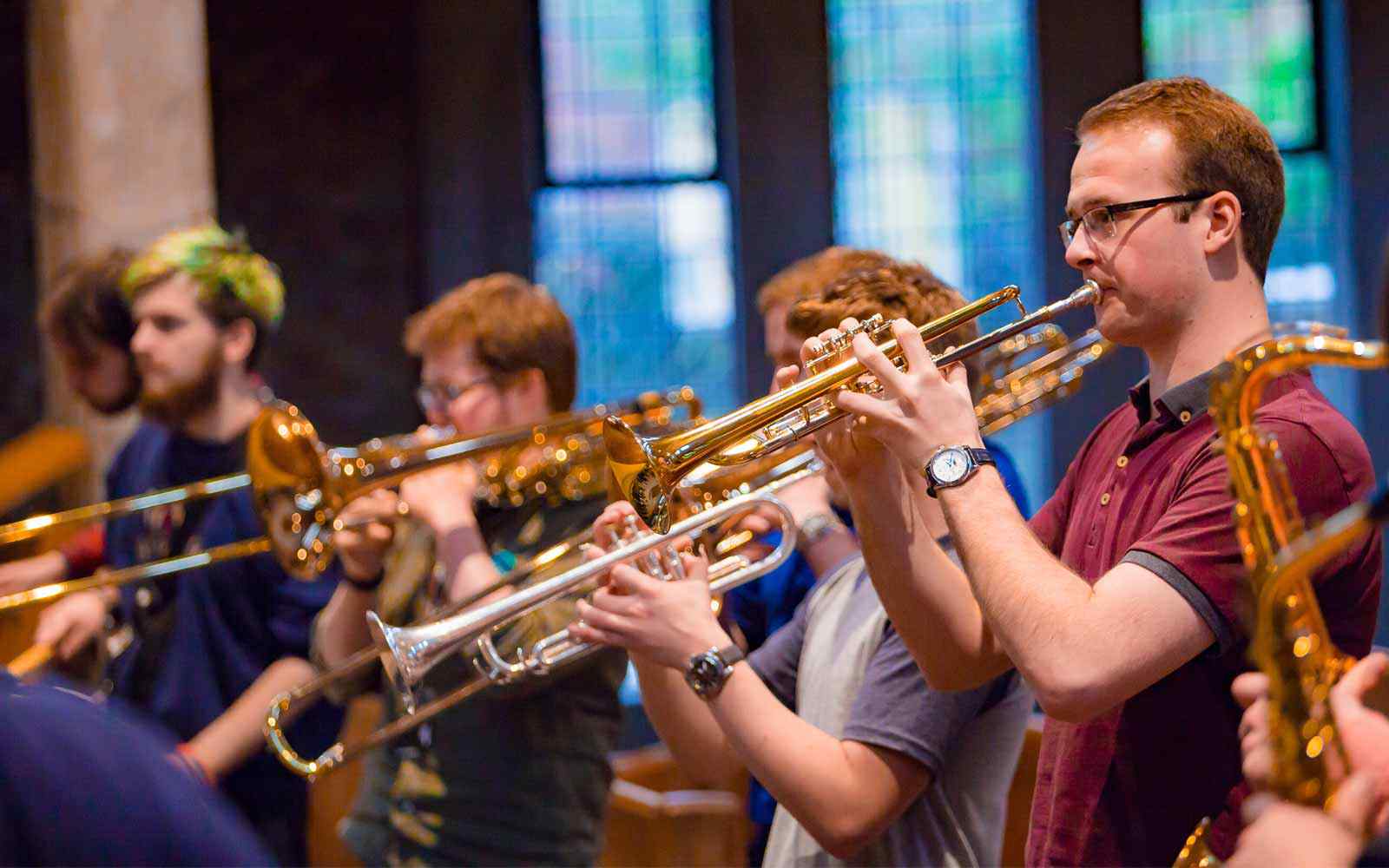 A group of students play brass instruments together in the university chapel. 