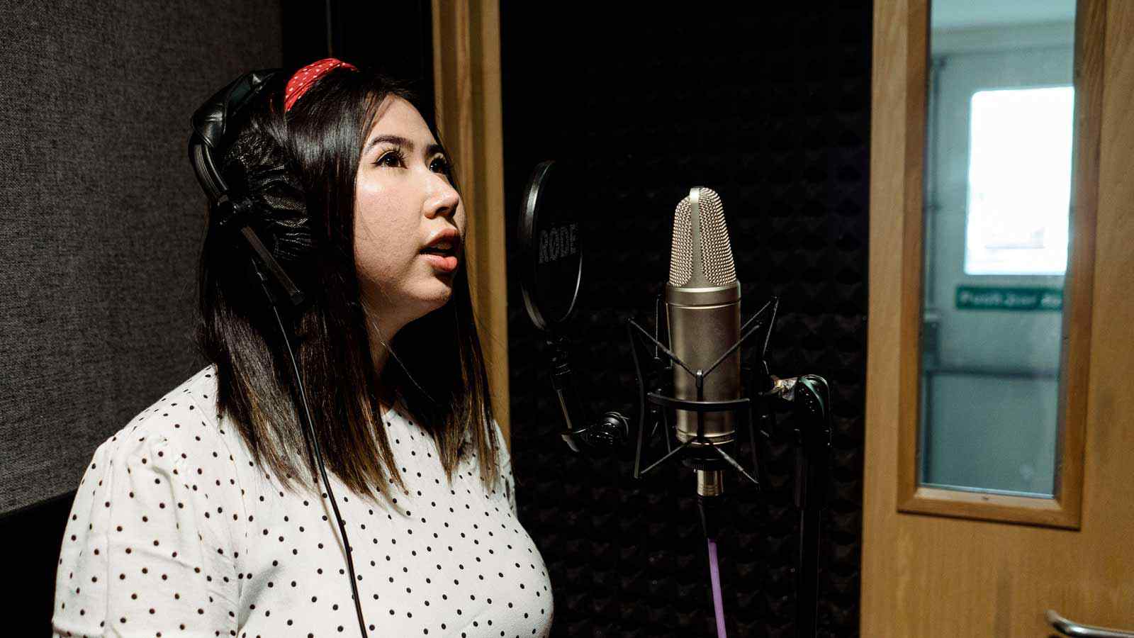 A music student sings in a recording booth. 