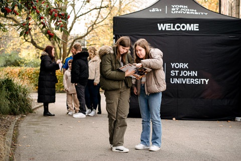 Two Open Day visitors looking at map in front of welcome tent 
