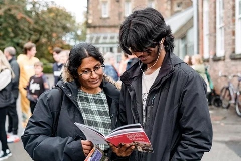A student and their family member look at an Open Day guide. 
