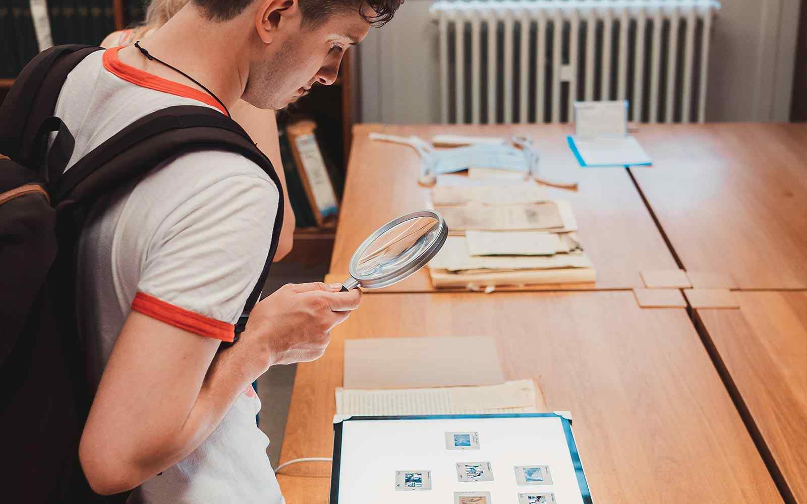 A student looking at artefacts through a magnifying glass 