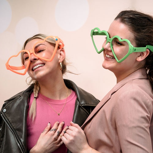 Two students wearing colourful glasses for photobooth photo 