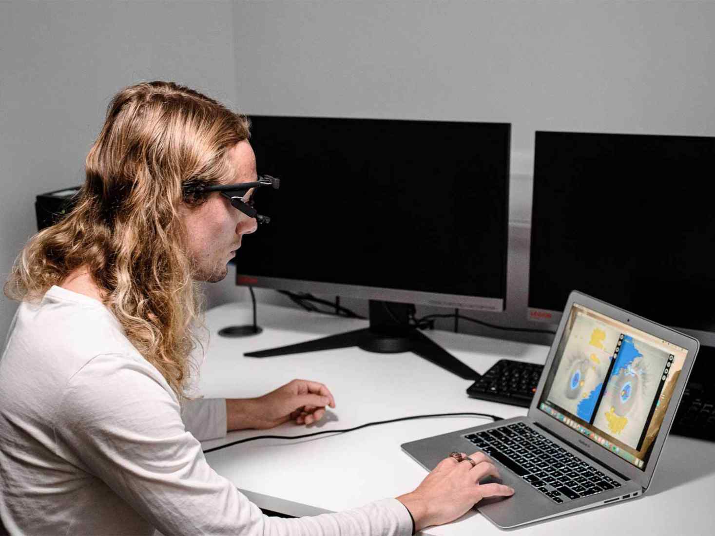  Person sitting in front of a laptop wearing an eye tracker 