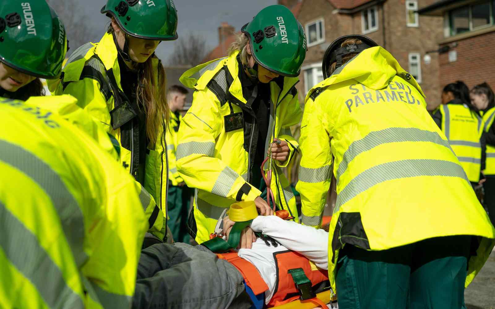 Students gather around a patient on a trolley during a Paramedic Simulation Day 