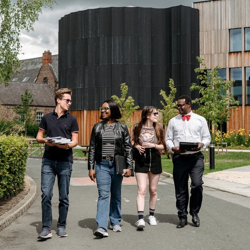 Four students walk together outside the Creative Centre. 