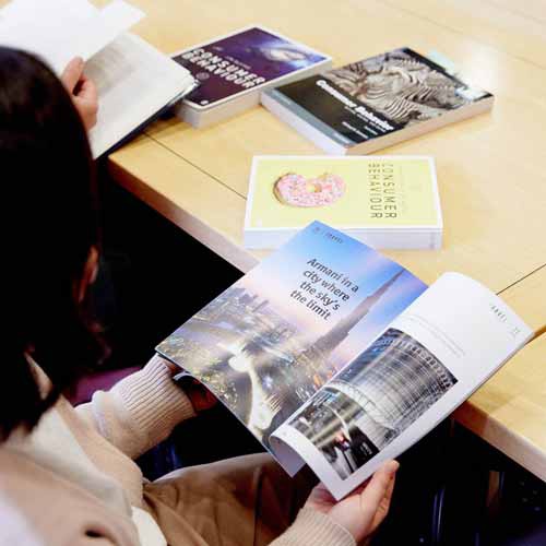 Student reading magazine with tourism advert 