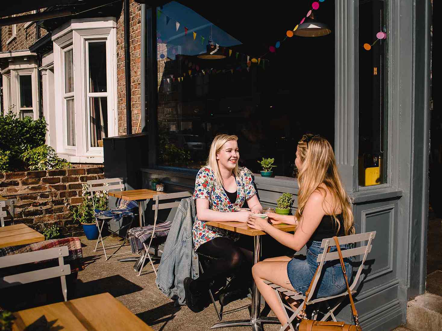 two students sat outside a cafe in the summer sun  