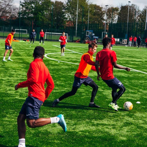 i2i Academy students playing football on a university pitch. 