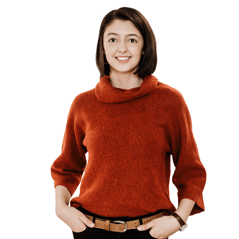 Brunette female student wearing red jumper, smiling at camera, hands on her hips 